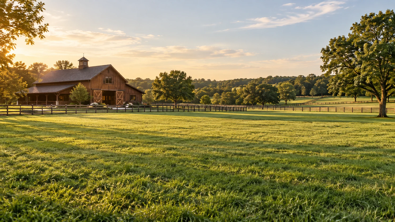 A timber barn, fenced paddocks and open green pasture